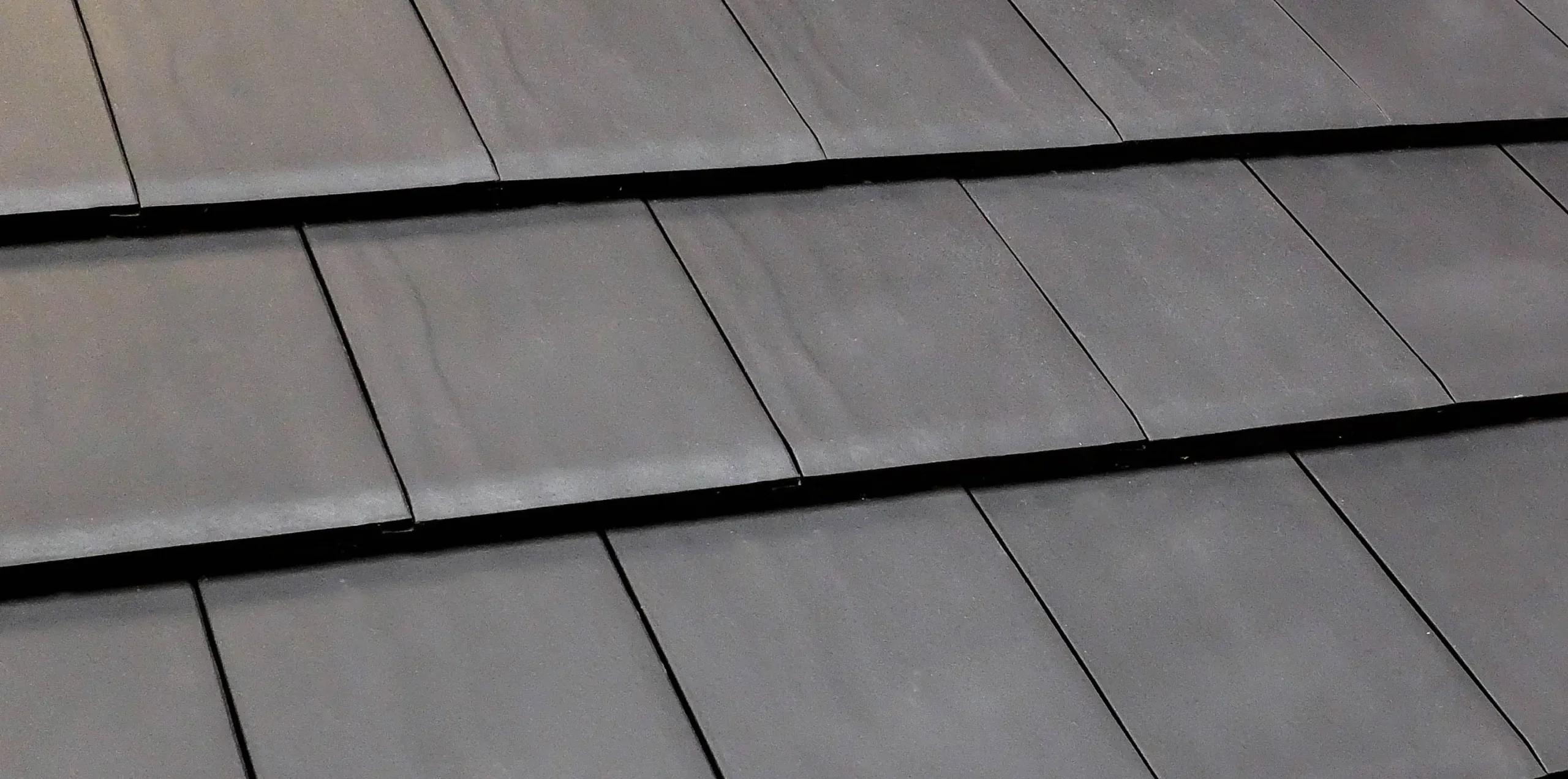 Black metal roof tiles overlapping rows