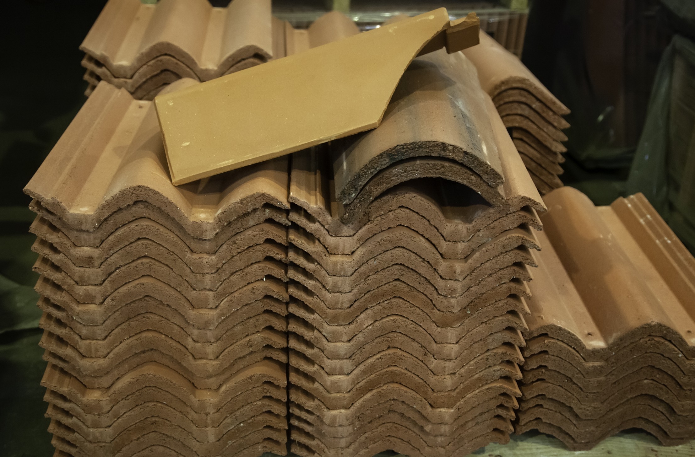 Stacked brown clay roof tiles in warehouse