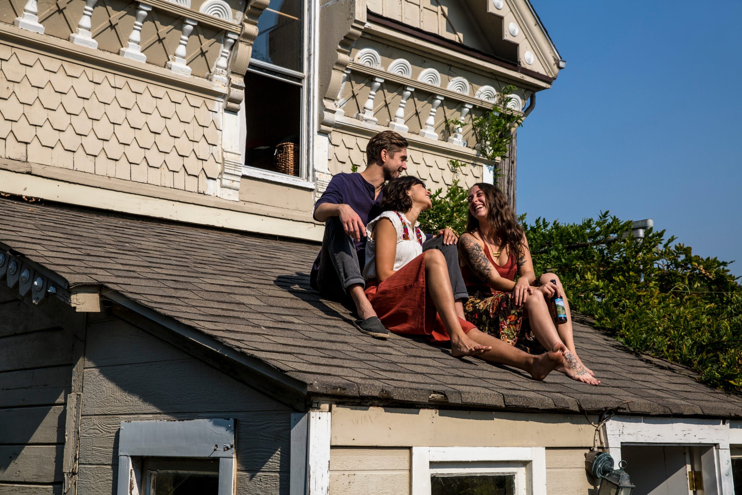 Friends sitting on house roof in sunlight