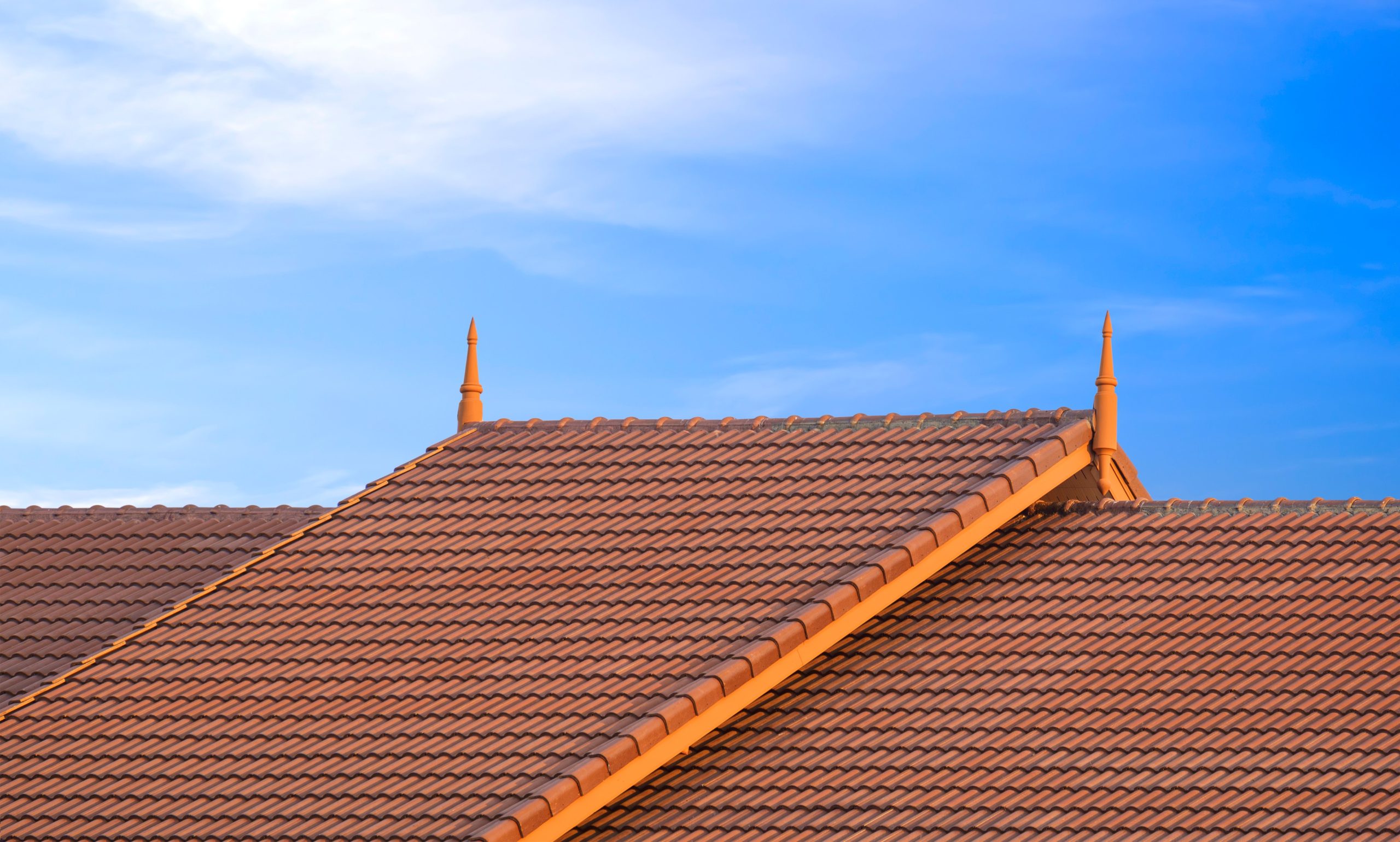 Orange tiled roof with finials and sky